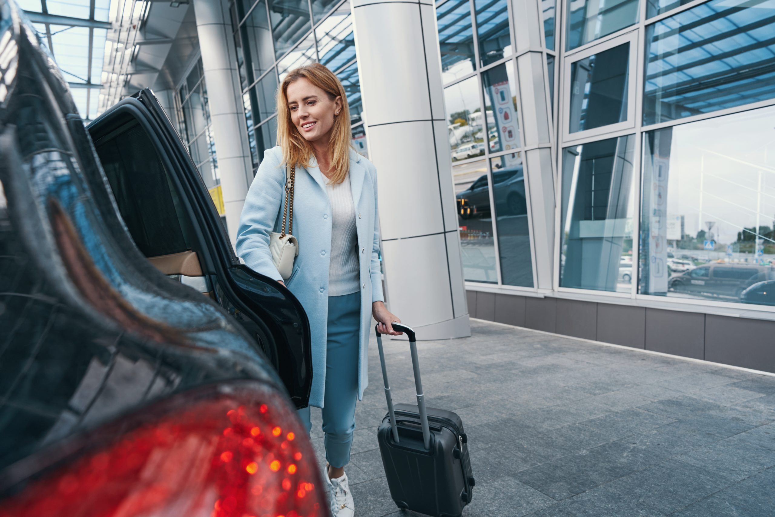 Voyageuse avec bagage devant un taxi pour un transfert vers l’aéroport de Bruxelles-Charleroi