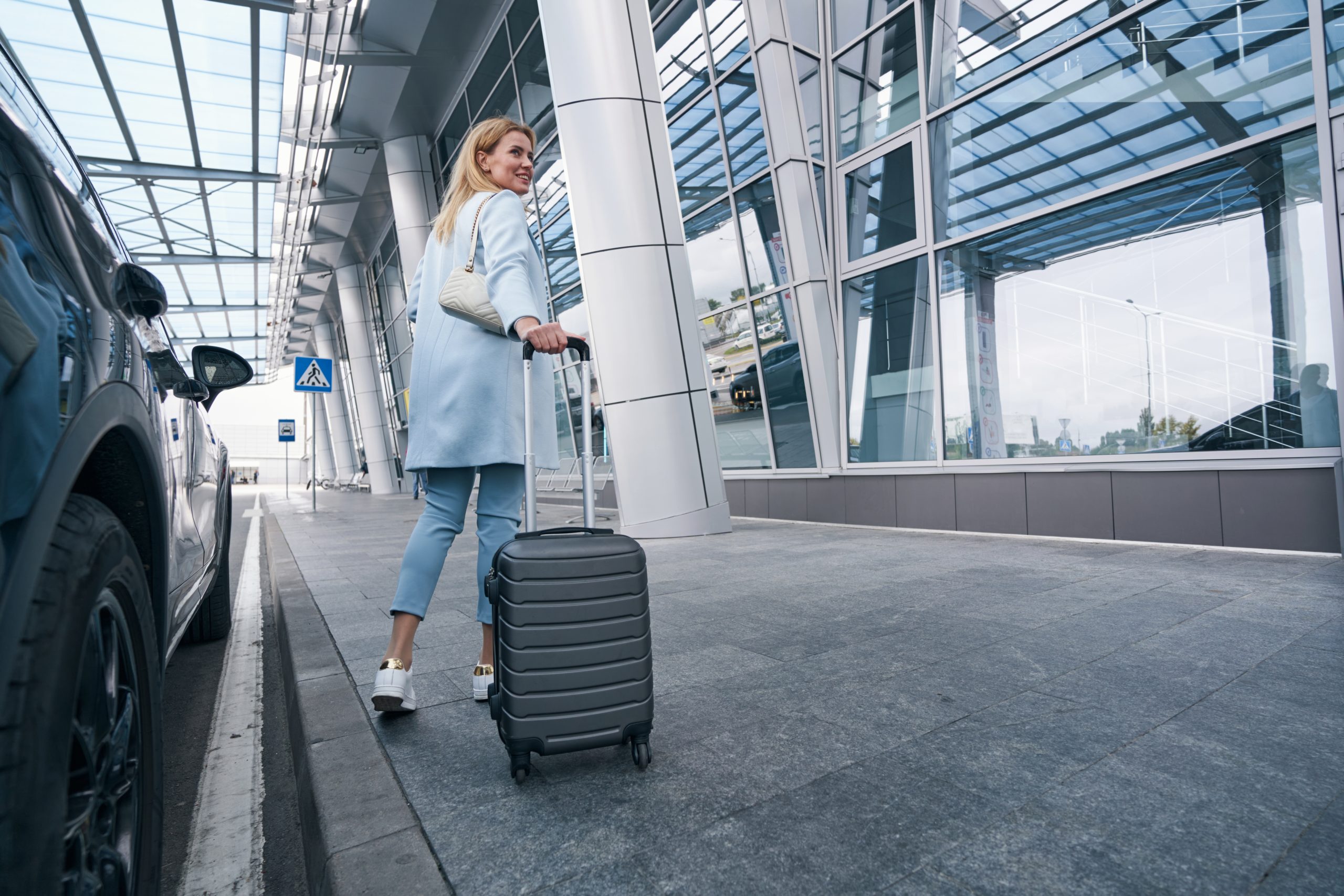 Voyageuse avec valise devant un véhicule pour un transfert vers l’aéroport Paris-Charles-de-Gaulle